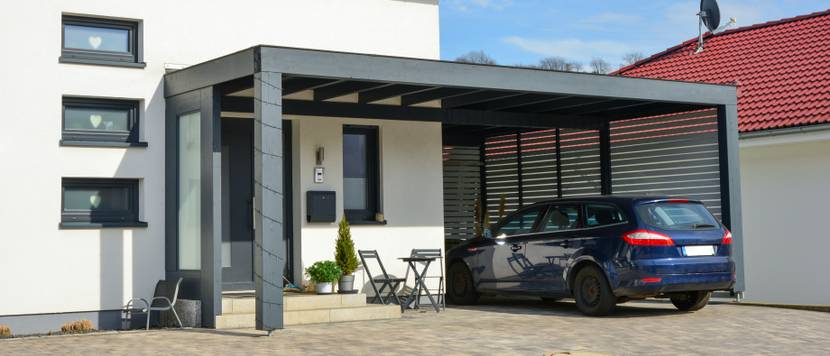 Moderner Carport aus lackiertem Holz im Einfahrtsbereich eines Wohnhauses.