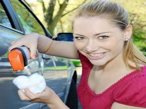 Frau bei Wagenwäsche poliert Auto mit Politur und Polierwatte