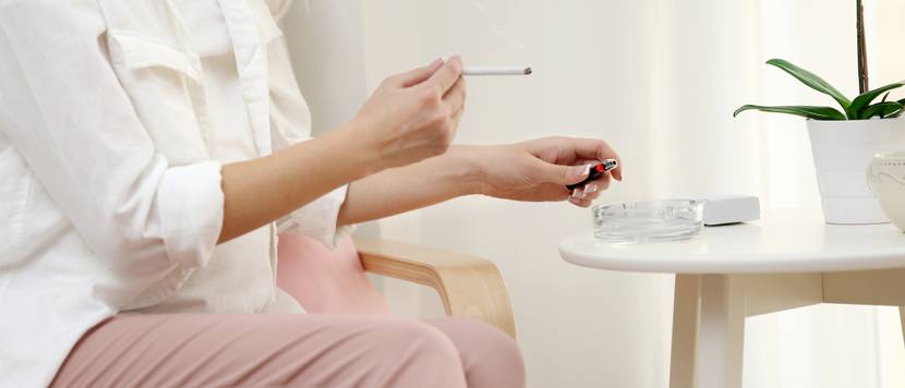 frau sitzt mit zigarette am tisch