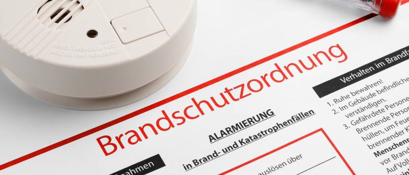 rauchmelder neben schraubenzieher und brandschutzverordnung