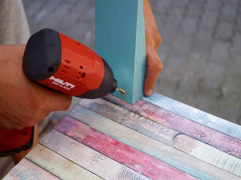 Die Keile mit Holzschrauben am Raumteiler befestigen und mit einem Klecks Farbe kaschieren