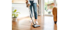 Eine Frau reinigt ihre Wohnung mit einem Staubsauger.