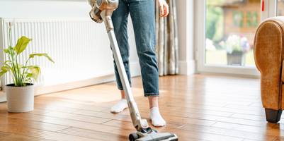 Eine Frau reinigt ihre Wohnung mit einem Staubsauger.
