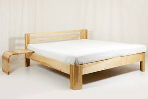 Massivholzbett im Test für Verbessern von Schlafqualität: Holzbett mit integriertem Nachttisch vor weißem Hintergrund.