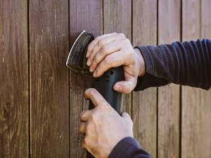 Schleifen mit Schwingschleifer auf altem Holz, Holzzaun wird angeraut