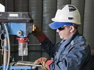 Craftsman drilling metal with drill in workshop