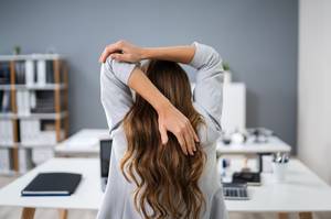 person dehnt sich am schreibtisch