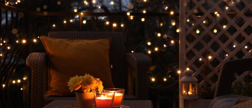 Gartenmöbel sind mit Lichterkette und Kerzen versehen.