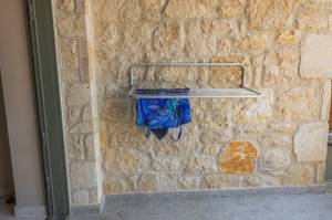 Wandtrockner hängt an einer Wand auf einer Terrasse. Auf den Wandtrockner wurde ein Badeanzug zum Trocknen gehängt.