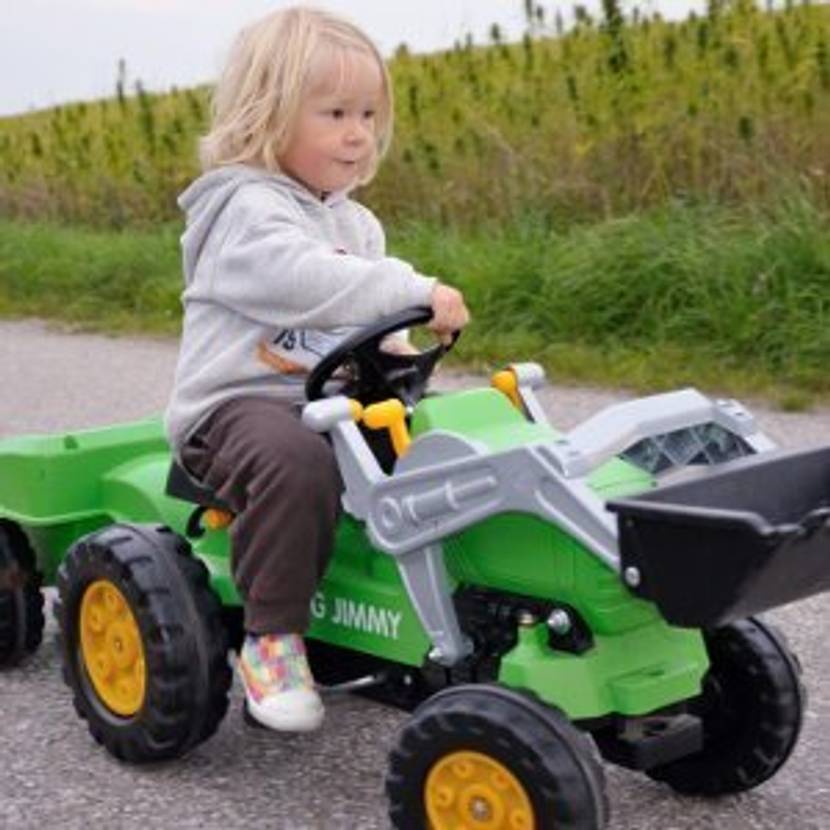 Kind lenkt grünen Trettraktor.