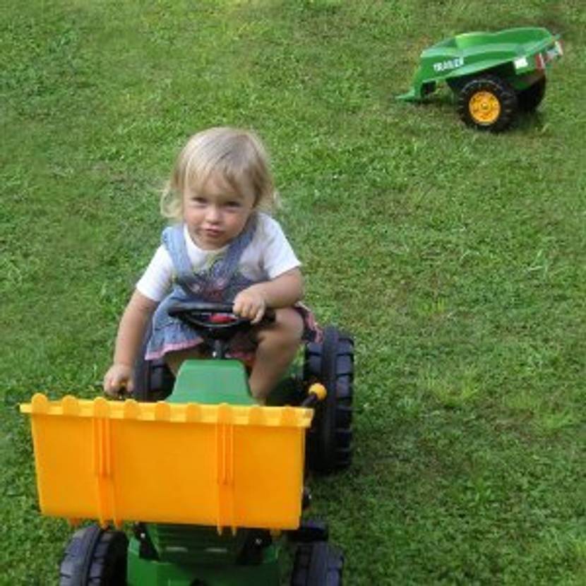 Trettraktor mit Anhänger im Hintergrund.
