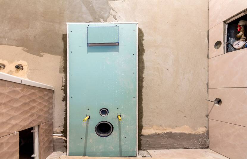 Vorwandelement für ein wandhängendes WC mit grüner Feuchtraumplatte, sichtbaren Anschlussöffnungen und Gewindestangen zur späteren Montage der WC-Keramik.