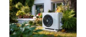 Eine mittelgroße Wärmepumpe steht im Garten eines Hauses.