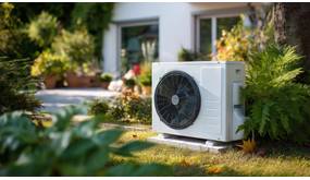 Eine mittelgroße Wärmepumpe steht im Garten eines Hauses.