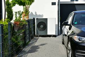 Luft-Wärmepumpe steht vor einem Wohnhaus