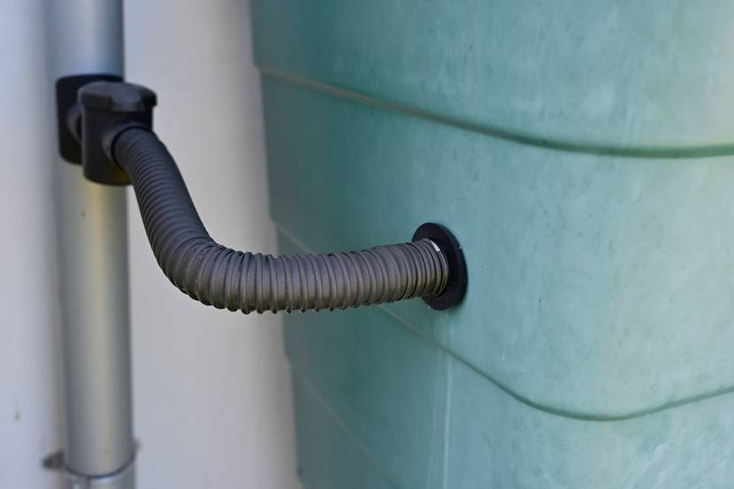 Ein Wassertank ist mit einer Leitung mit einer Regenrinne verbunden.