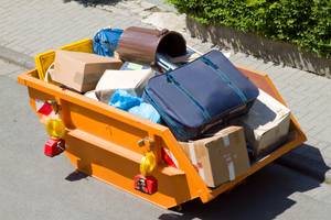 Wohnung aussortieren: Container mit Kartons und alten Gegenständen.