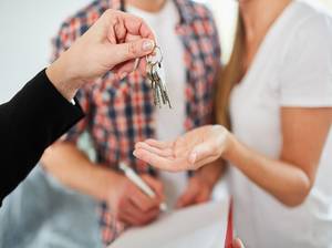Makler übergibt Schlüssel für Wohnung oder neues Haus als Eigenheim an Paar
