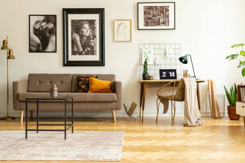 An der Wand eines modernen Wohnzimmers hängen mehrere Bilder in verschiedenen Größen und mit unterschiedlichen Rahmen.