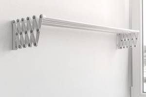 Zusammengeklappter Scheren-Wandtrockner aus Metall vor einer hellen Wand.